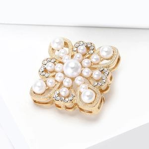 Macro detail of royal baroque clover brooch with pearls and crystals in gold finish