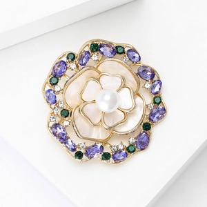 Détail de la broche fleurie avec pierres violettes et perle blanche sur base dorée