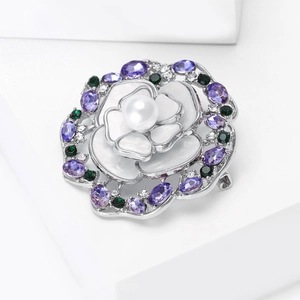 Gros plan sur la broche camélia avec pétales en nacre, gemmes violettes et perle d'eau douce