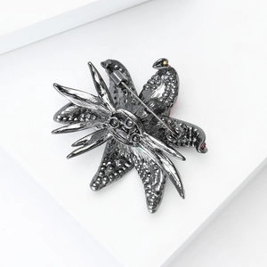 Detail view of gun-black lily octopus brooch with red rhinestones and secure pin back