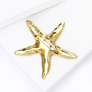 Vue arrière d'une broche étoile de mer dorée avec texture martelée sur socle blanc