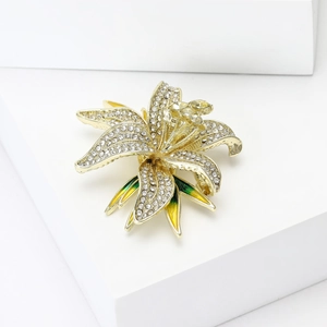 Detailed macro view of crystal-encrusted lily brooch with green enamel leaves on gold base