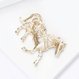 Back view of a golden horse brooch with detailed metal texture and pin closure