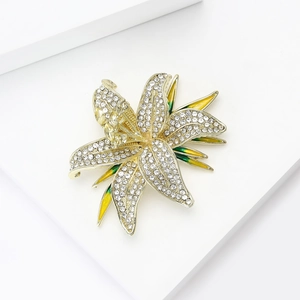 Macro shot of lily flower brooch featuring white rhinestones and green enamel petals