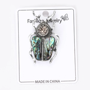 Vue détaillée de la broche scarabée en argent vintage et ses ailes en nacre d'abalone irisées