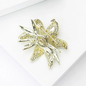 Macro detail of the golden lily brooch back with a secure pin clasp and textured finish