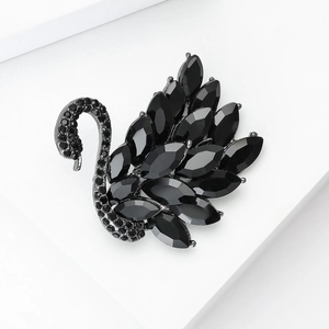 Detalle de un lujoso broche de cisne negro con cristales sobre una superficie blanca pura