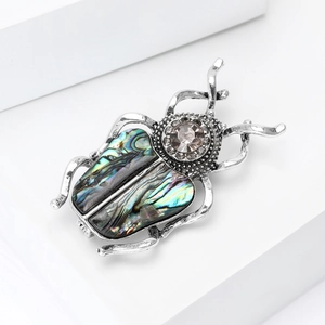Détail de la broche scarabée avec des ailes en nacre d'abalone et tête en cristal