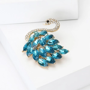 Detalle de elegante broche de cisne dorado con gemas marquesas azules y cristales finos