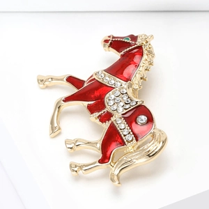 Macro detail of a red enamel horse brooch with sparkling rhinestones and gold-plated finish