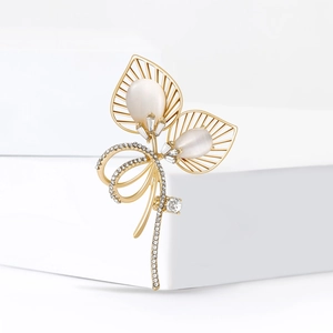 Broche bouquet dorée avec pierres œil-de-chat et cristaux pavés sur socle blanc