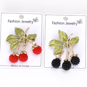Detail of red and black enamel berry brooches with golden stems on fashion jewelry cards