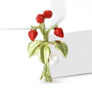 Broche fraise en émail avec feuilles vertes et perle sur un fond blanc minimaliste