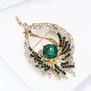 Dettaglio di una spilla a pavone con pietra verde taglio smeraldo e cristalli scintillanti
