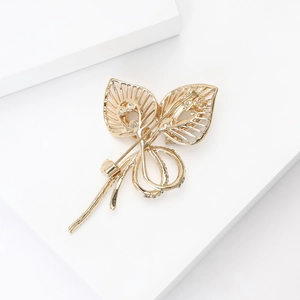 Élégante broche feuille dorée ajourée avec pierre œil de chat et strass sur socle blanc