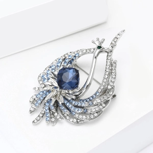 Primo piano di una spilla a forma di pavone argento con cristallo ovale blu intenso