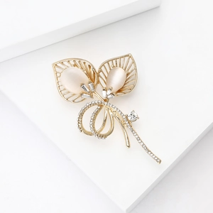 Détail macro d'une broche en forme de feuille avec pierres œil de chat et strass