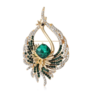 Elegante spilla a pavone dorata con strass verdi e gemma quadrata su sfondo bianco