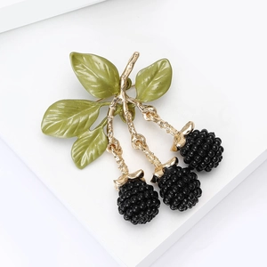 Macro detail of enamel blackberry brooch with black beads and green leaves on white stand