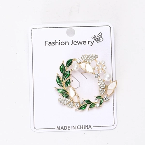 Détail de la broche couronne de Noël avec feuilles en émail vert, perles et papillon