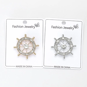 Dettaglio di spille a timone con strass in finitura oro e argento su scheda display