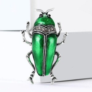 Broche scarabée vintage en émail avec laque verte et strass gris sur fond blanc épuré
