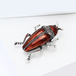 Détail d'une broche scarabée vintage avec émail rougeâtre et strass étincelants
