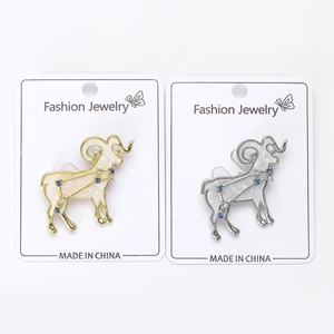 Close-up of Aries goat brooches in gold and silver finish with rhinestones and enamel
