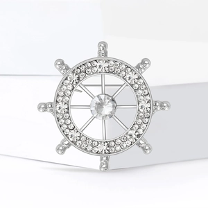 Elegante spilla a timone d'argento con strass scintillanti su sfondo geometrico bianco