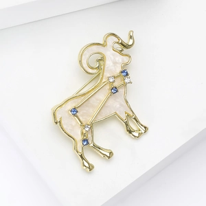 Detailed macro view of Aries zodiac brooch in gold alloy with white marble enamel and rhinestones