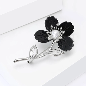 Détails d'une broche fleur en résine noire avec texture de feuille en métal argenté
