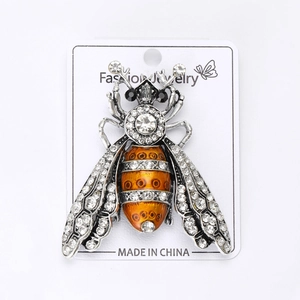 Macro shot of silver bee brooch with sparkling rhinestones and orange enamel belly