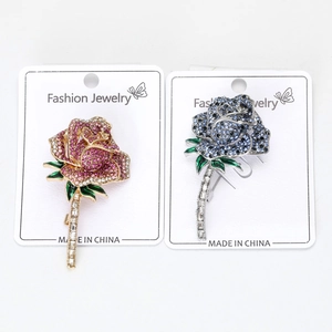 Detail of elegant rose brooches with rhinestones and enamel on a display card