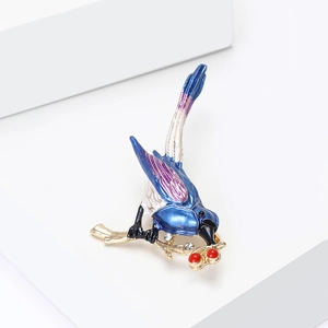 Detail van blauwe en paarse emaille vogelbroche op gouden tak met witte kristallen