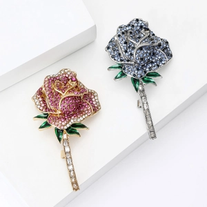 Elegant rose brooches with pink and blue crystals on white geometric background