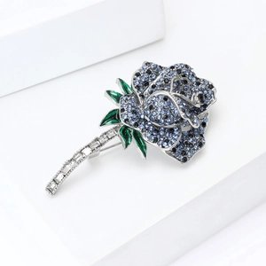 Macro shot of blue crystal rose brooch with emerald green leaves and silver alloy stem