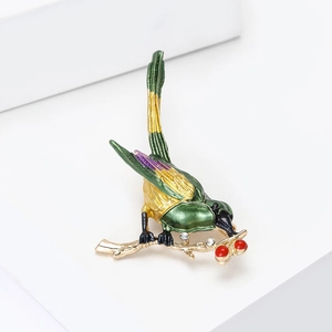 Macro-opname van een emaille vogelbroche met gouden takjes en sprankelende kristallen