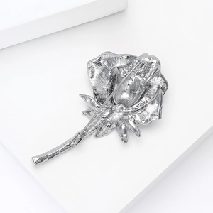 Back view of silver rose brooch showing secure pin fastener and textured alloy finish