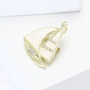 Élégante broche voilier dorée avec émail blanc et strass brillants pour vêtements chics