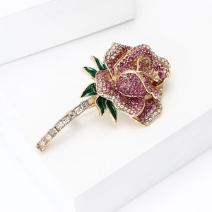Detailed macro of crystal rose brooch with pink rhinestones and green enameled leaves