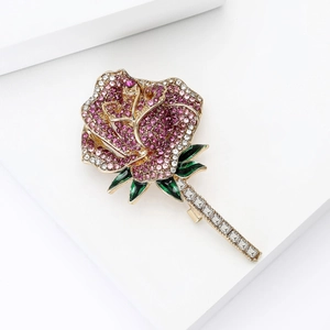 Macro view of crystal rose brooch with pink rhinestones and green enamel leaves