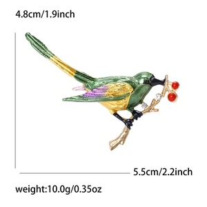 Elegante geëmailleerde vogelbroche met groen en gele afwerking en rode kralen