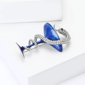 Détail d'une broche verre à martini en émail bleu avec serpent serti de cristaux brillants