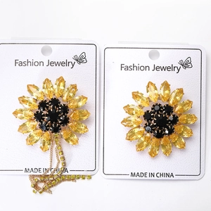 Detailed close-up of crystal sunflower brooch with yellow petals and sparkling tassels