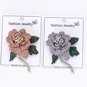 Detail of rose brooches set with pink and purple rhinestones on a gold and silver base
