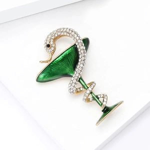 Détail de la broche serpent en strass enroulé autour d'un verre à martini en émail vert