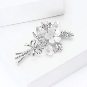 Gros plan d'une broche élégante en bouquet de fleurs avec pétales blancs et cristaux
