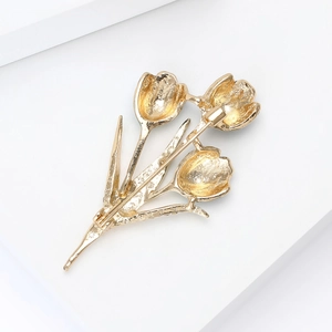 Elegant gold-tone tulip flower brooch set against a minimalist white geometric display base