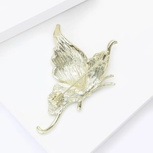 Detailed view of the golden butterfly brooch back with fine metal texture and pin clasp