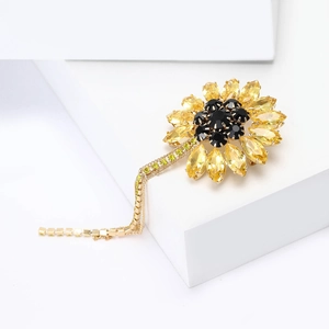 Detailed view of sunflower brooch with yellow crystals and golden fringe chain detail